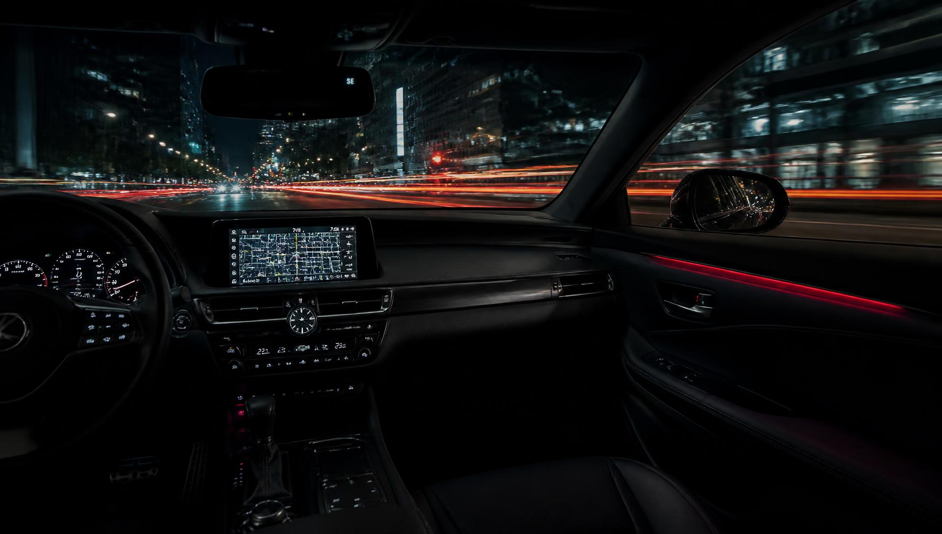 View across a dark car dashboard at night with city light trails through the windshield
